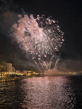 Alicante İspanya 'nın deniz kenarında gece gökyüzünde güzel renkli havai fişekler.