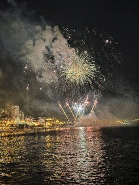 Alicante İspanya 'nın deniz kenarında gece gökyüzünde güzel renkli havai fişekler.