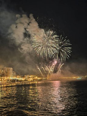 Alicante İspanya 'nın deniz kenarında gece gökyüzünde güzel renkli havai fişekler.