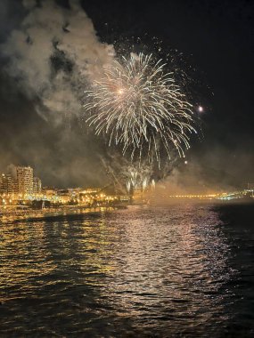 Alicante İspanya 'nın deniz kenarında gece gökyüzünde güzel renkli havai fişekler.