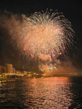 Alicante İspanya 'nın deniz kenarında gece gökyüzünde güzel renkli havai fişekler.