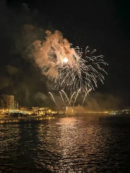 Alicante İspanya 'nın deniz kenarında gece gökyüzünde güzel renkli havai fişekler.