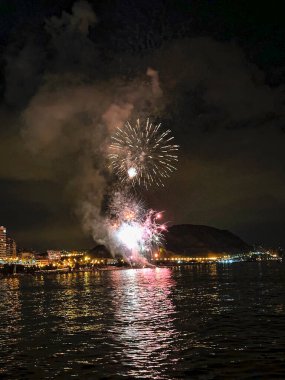 Alicante İspanya 'nın deniz kenarında gece gökyüzünde güzel renkli havai fişekler.