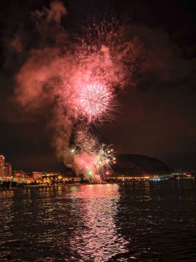 Alicante İspanya 'nın deniz kenarında gece gökyüzünde güzel renkli havai fişekler.