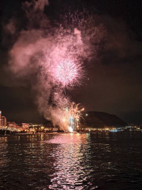 Alicante İspanya 'nın deniz kenarında gece gökyüzünde güzel renkli havai fişekler.