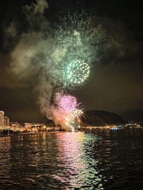 Alicante İspanya 'nın deniz kenarında gece gökyüzünde güzel renkli havai fişekler.