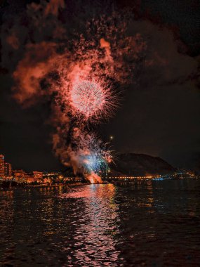 Alicante İspanya 'nın deniz kenarında gece gökyüzünde güzel renkli havai fişekler.