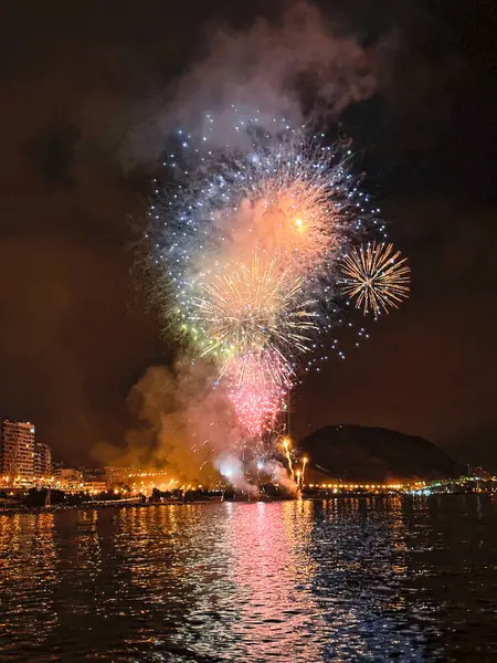 Alicante İspanya 'nın deniz kenarında gece gökyüzünde güzel renkli havai fişekler.