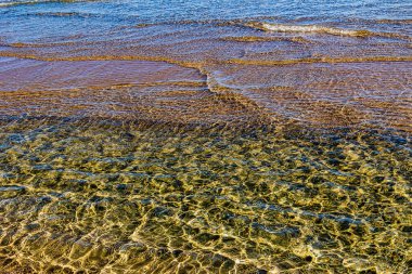 Güneşli bir günde kıyı boyunca dalgalanan berrak deniz suyunun güzel arka planı