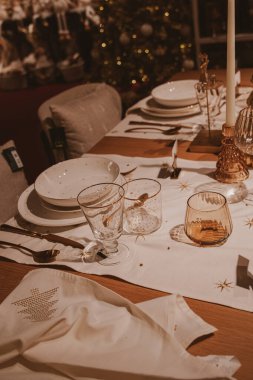 A beautifully set dining table features elegant dinnerware and glassware, along with a decorative candle as its centerpiece clipart