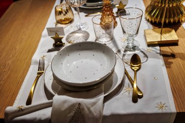 A beautifully set dining table features elegant dinnerware and glassware, along with a decorative candle as its centerpiece clipart