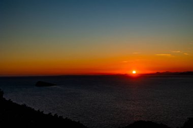 Huzurlu bir gün batımı ufkun üzerinde ılık bir turuncu parıltı bırakır.