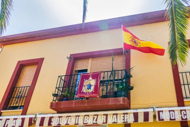 Binanın ön cephesinde canlı bir İspanyol bayrağı saksı bitkileriyle süslenmiş küçük bir balkonda sergileniyor..