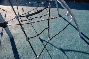 Çocukların oyun sahasına tırmanmak, ağa tırmanmak, oyun parkında ipler tırmanmak, tırmanmak için tırmanmak. Çocuklar için renkli lastik döşemeli modern oyun parkı.