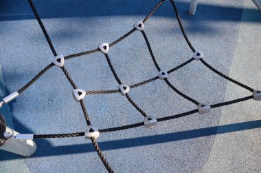 Çocukların oyun sahasına tırmanmak, ağa tırmanmak, oyun parkında ipler tırmanmak, tırmanmak için tırmanmak. Çocuklar için renkli lastik döşemeli modern oyun parkı.