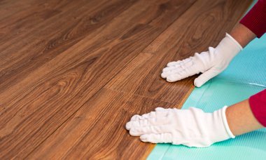 Beyaz eldivenli bir zanaatkar köpük tabakasına ahşap kaplama serer.