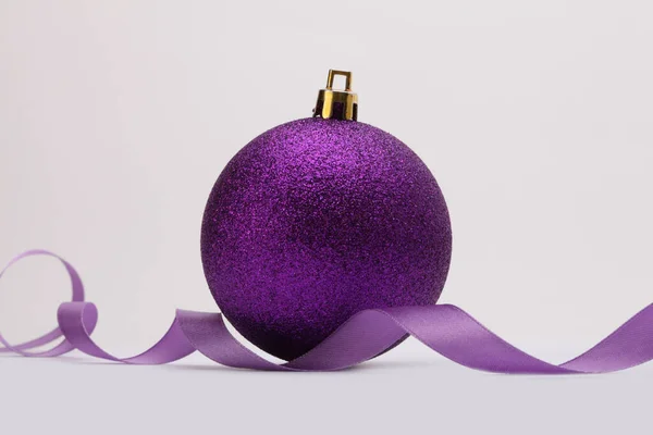 クローズアップバイオレットの輝きの質感の真珠層と輝きメリークリスマスボール ベージュの背景にリボン — ストック写真