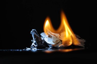 Burning paper log and fire on black.