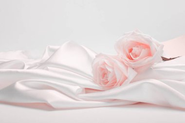 Wave fabric silk with beige pink rose flower bouquet. Abstract texture horizontal copy space background.