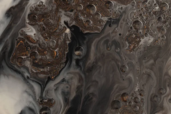 Flow pour wave oil and acrylic color painting blot and drop wall. Abstract swirl black and bronze texture background.