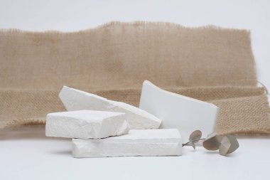 Stack Stones platform podyumu ve okaliptüs yaprağı, gri ışık fotokopisi arka planında. En az boş ürün sunum sahnesi.