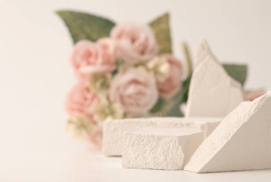 Boş taş yığını platform podyumu ve bej arka planda gül çiçeği buketi. En az boş ürün sunum sahnesi.