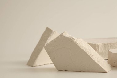 Açık bej arka planda doku taşı eko podyumu. En az canlı ürün sunum sahnesi.