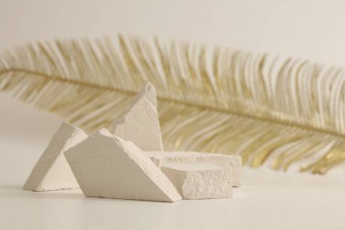 Doku taşı eko podyum ve açık bej arka planda altın yaprak. En az canlı ürün sunum sahnesi.