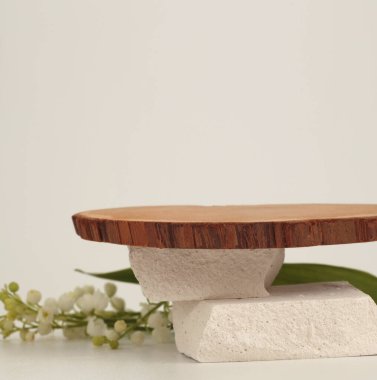 Ahşap disk yığını, taş platformu podyumu ve bej ışıklı arka planda çiçek. En az boş ürün sunum sahnesi.