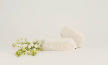 Bej ışıklı arka planda taş yığını platform podyumu ve çiçek kar damlası. En az boş ürün sunum sahnesi.