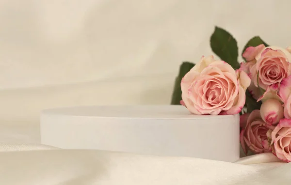 粉红玫瑰花束点缀在白色的讲台上和丝织品上浅浅的米色背景 最小空显示产品演示场景 — 图库照片