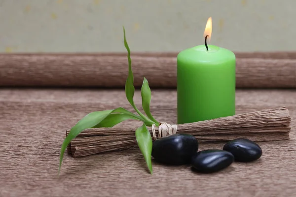 Brennende Grüne Kerze Schwarze Steine Und Bambusblatt Auf Braunem Mattenhintergrund — Stockfoto
