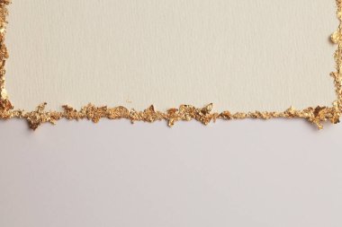 Bej rengi gri kağıdın arka planında altın (bronz) parıltılı boş tuval çerçeve. Soyut kopyalama alanı dokusu.