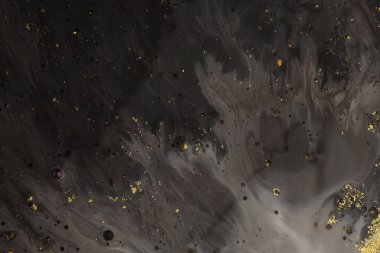 Akan yağ ve akrilik renkli boya sıvıya bulanır. Soyut siyah ve altın parıltılı doku arkaplanı.