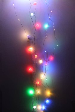 Yumuşak odak bulanıklığı koyu duvar arka planında Noel çelengi ışıkları.