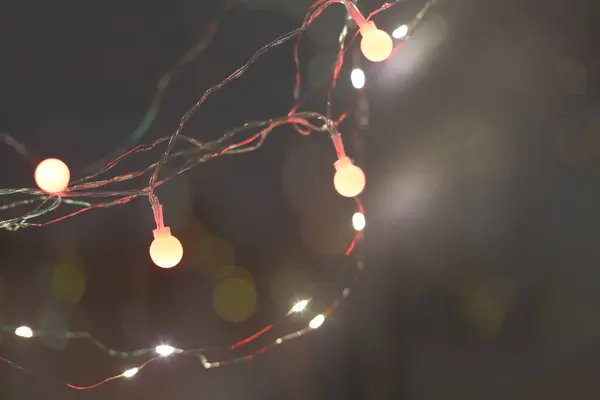 柔らかい焦点の煙は暗い壁の背景のクリスマスの色のガーランド ライトをぼやけます — ストック写真