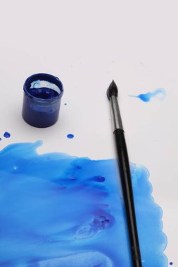 Boya fırçası ve mürekkep mavisi kağıt arkaplanda leke bırakıyor.