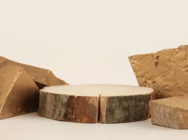 Taşlar, açık bej arka planda tahta disk platformu. En az boş ürün sunum sahnesi.