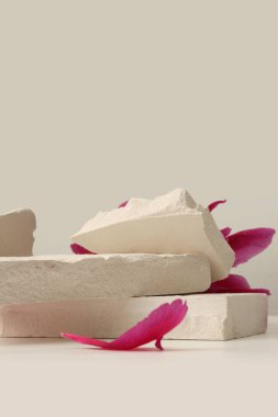 Mor pion çiçekli taç yaprağı ve bej renksiz arka planda taş platformu. En az boş ürün sunum sahnesi.