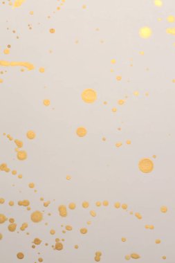 Altın, simli mürekkep suluboya bej kağıt desenli arkaplanda leke bırakıyor.