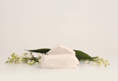 Bej ışıklı arka planda taş yığını platform podyumu ve çiçek kar damlası. En az boş ürün sunum sahnesi.