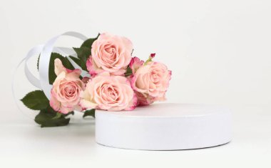 Pembe gül buketi ve beyaz podyum. Açık bej arka plan. En az boş ürün sunum sahnesi.