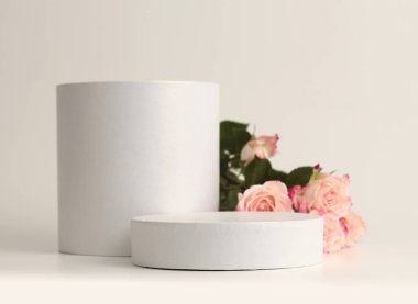 Pembe gül buketi ve beyaz podyum. Açık bej arka plan. En az boş ürün sunum sahnesi.