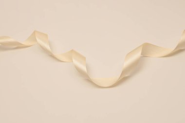 Tarafsız arkaplanda açık gölgeli bej renkli nacre renk dalgası ipek kurdelesi.