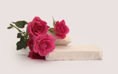 White Stones platformu podyumu, bej renkli gri ışıklı arka planda pembe kırmızı gül çiçeği buketi. En az boş ürün sunum sahnesi.