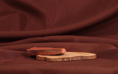 Kahverengi ipek kumaş arka planda tahta kütük ve taş platform podyumu. En az boş ürün sunum sahnesi.