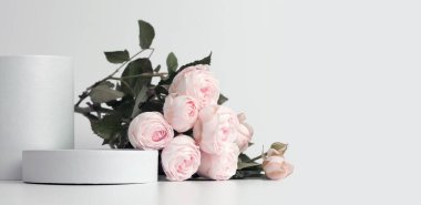 Beyaz podyumda bej pembe gül buketi. Açık gri nötr yatay arkaplan. En az boş ürün sunum sahnesi.