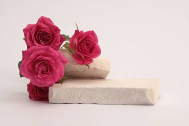 White Stones platformu podyumu, bej renkli gri ışıklı arka planda pembe kırmızı gül çiçeği buketi. En az boş ürün sunum sahnesi.