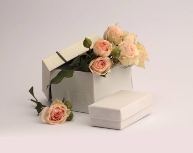 Gri tarafsız arka planda bej kremalı gül buketli el işi hediye kutuları. Ürün sunumu sahnesi için en az boş kaide podyumu.