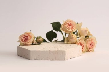 Stones platformu podyumu, gri arka planda bej kremalı gül çiçeği buketi. Ürün sunum sahnesi için en az boş temel.